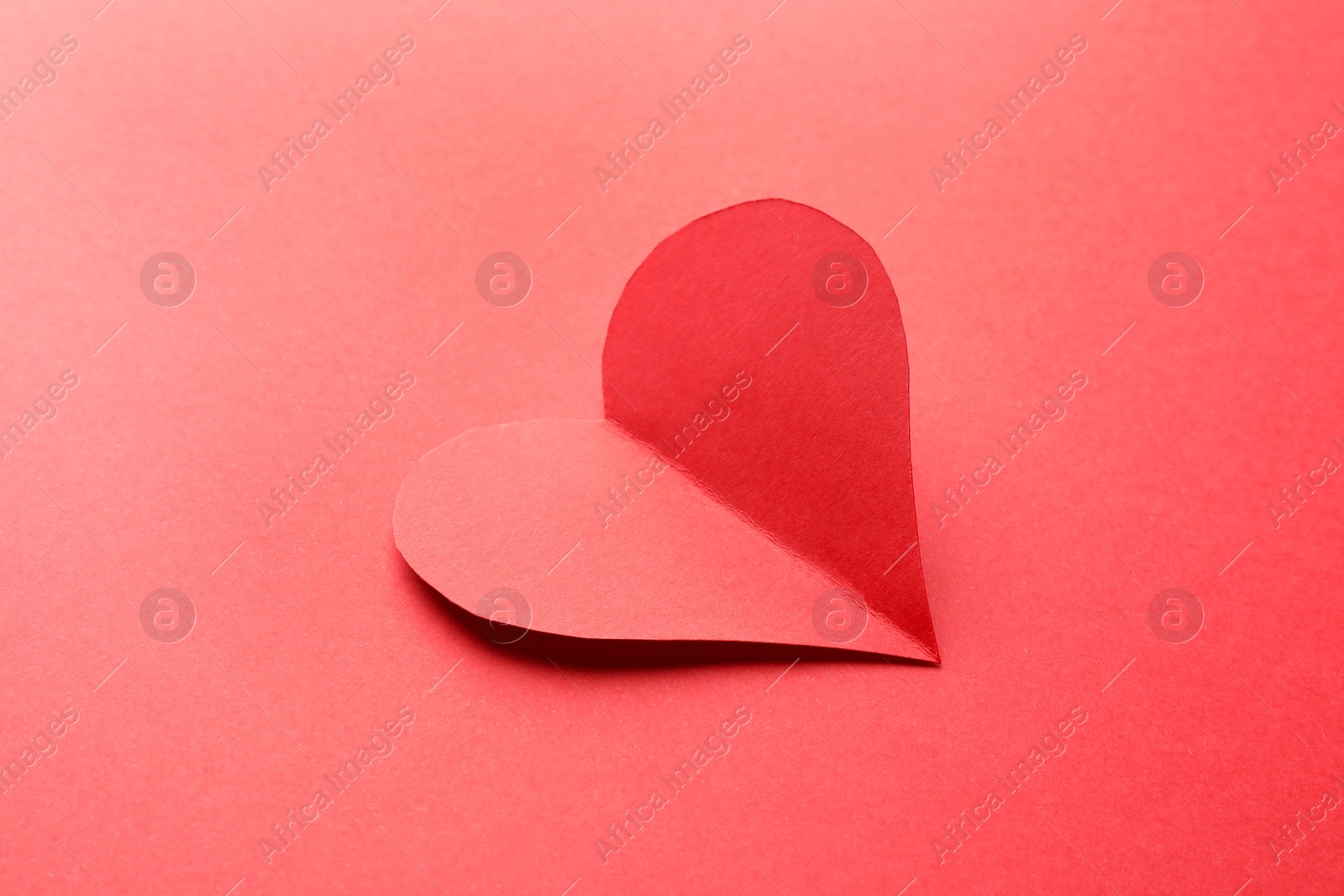 Photo of One bright paper heart on red background