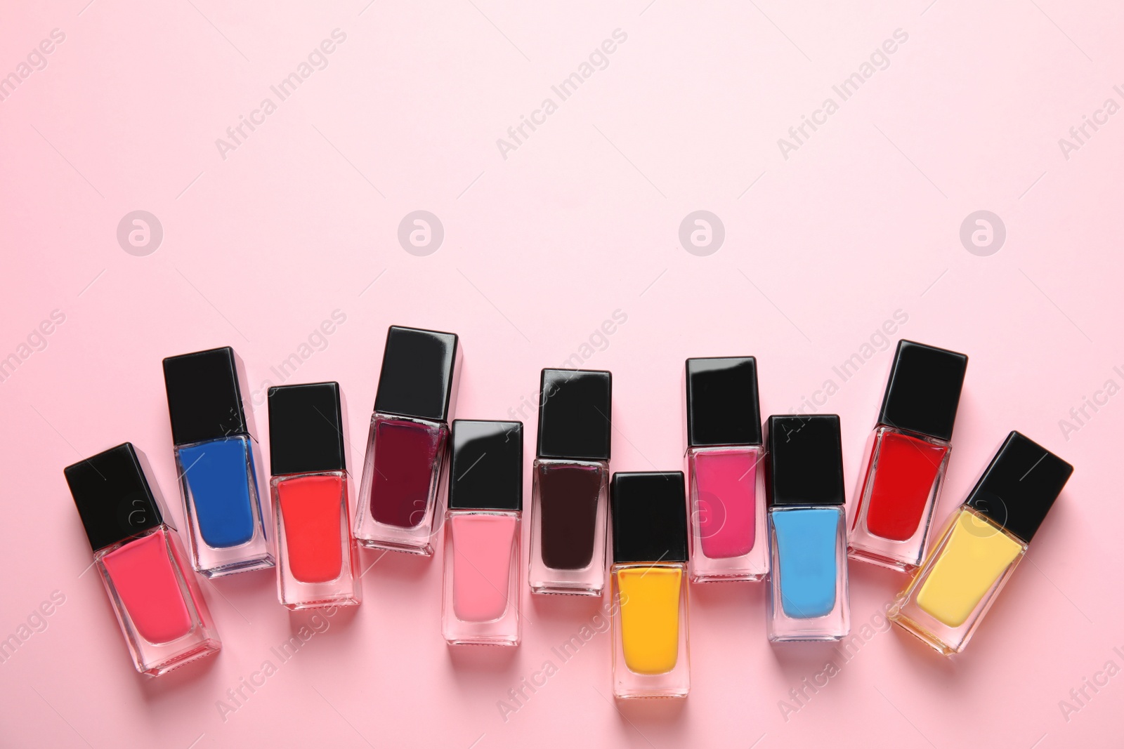 Photo of Bottles of nail polish on color background, top view with space for text