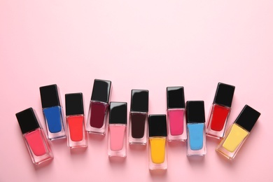 Bottles of nail polish on color background, top view with space for text