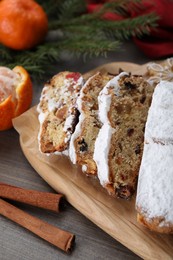 Photo of Traditional Christmas Stollen with icing sugar on wooden table, closeup