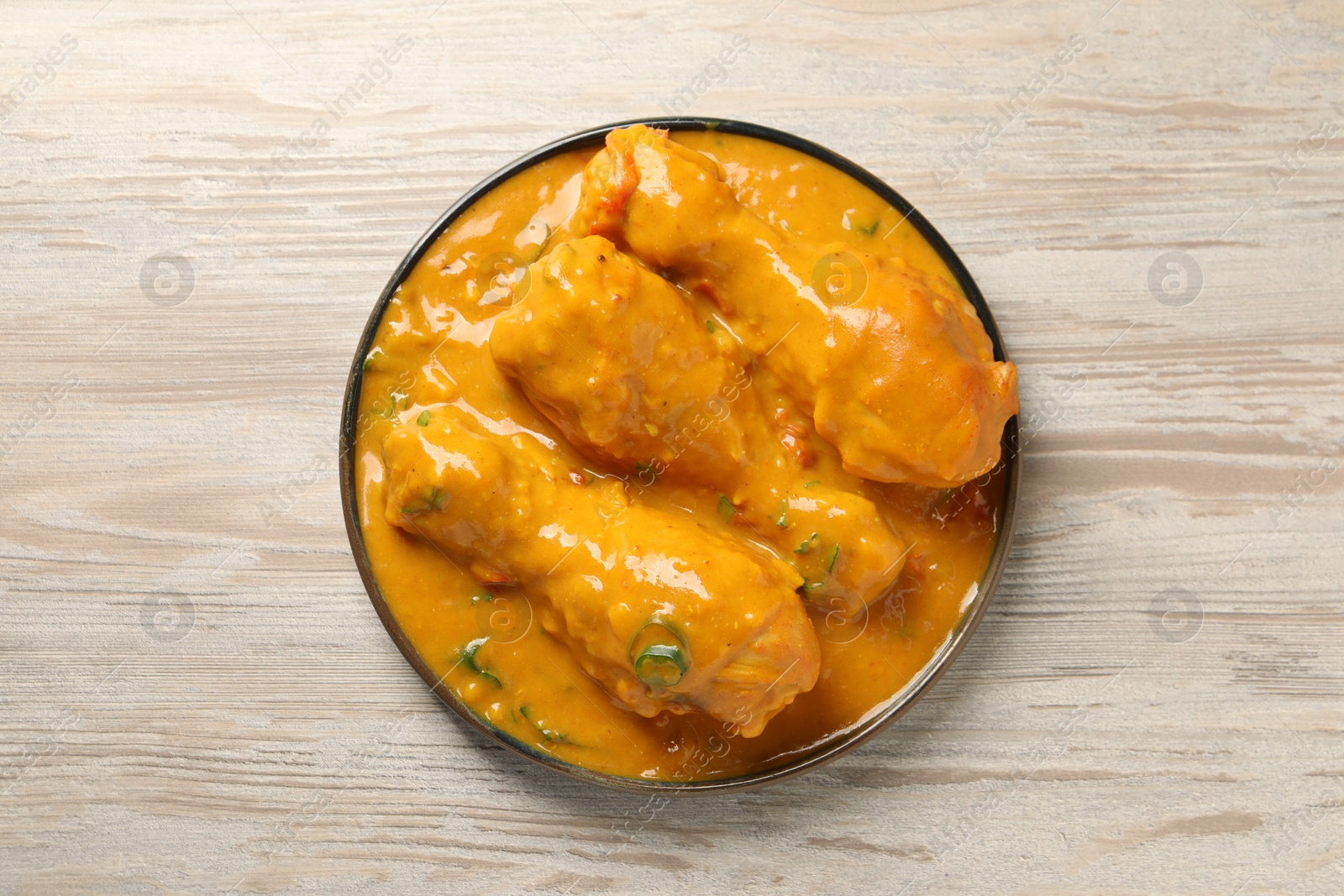 Photo of Tasty chicken curry on wooden table, top view