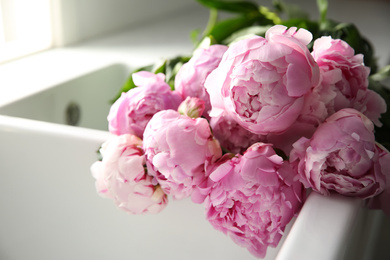 Photo of Bouquet of beautiful pink peonies in kitchen sink, closeup