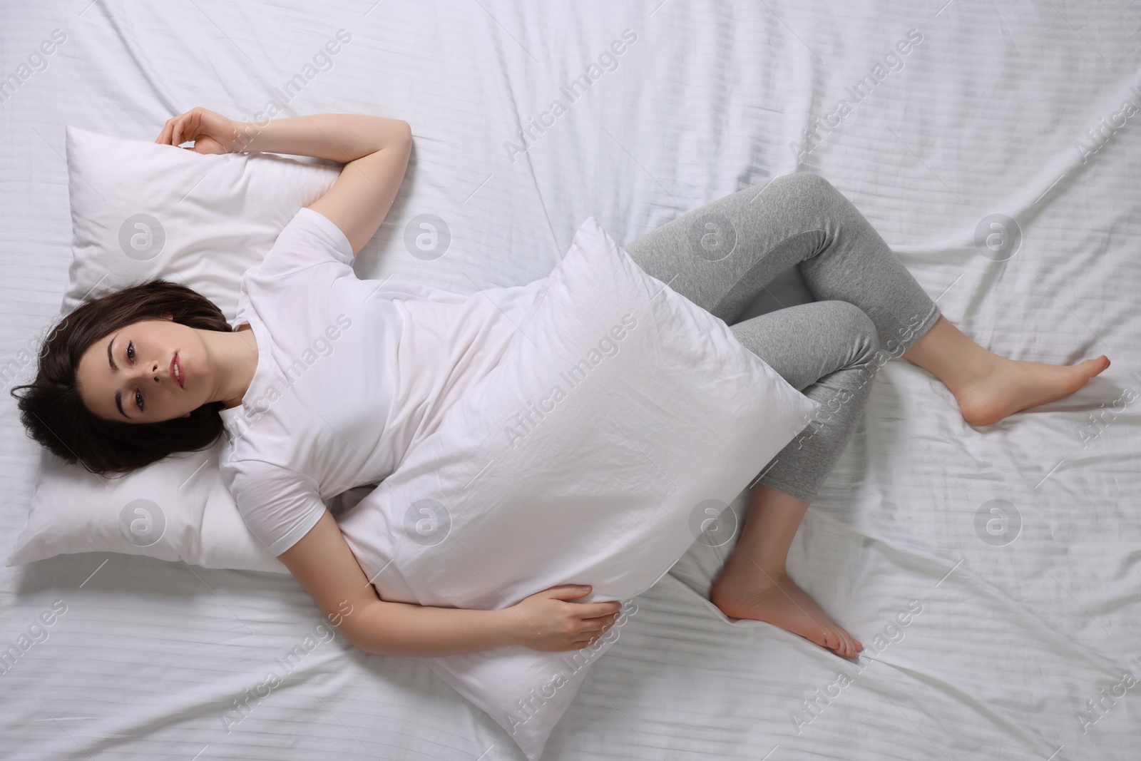 Photo of Young woman suffering from insomnia in bed, top view