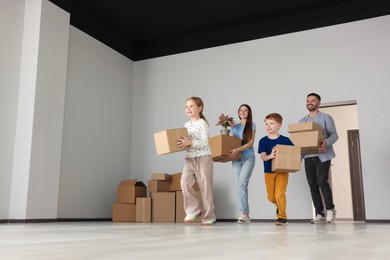 Photo of Happy family with moving boxes entering in new apartment. Settling into home