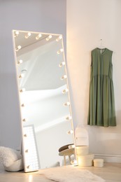 Large mirror with light bulbs near white wall in stylish room. Interior design