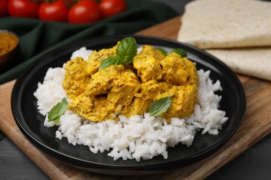 Photo of Delicious rice and chicken with curry sauce on wooden board, closeup