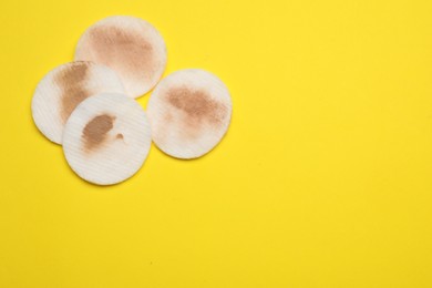 Photo of Dirty cotton pads after removing makeup on yellow background, flat lay. Space for text