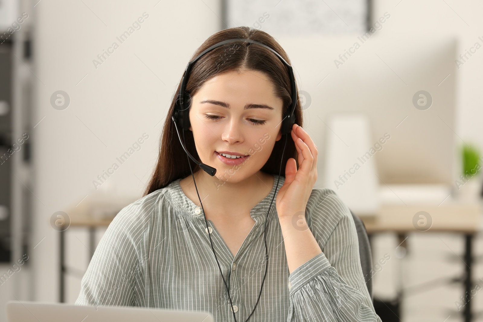 Photo of Hotline operator with headset working on laptop in office