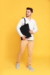 Full length portrait of young man with eco bag on yellow background