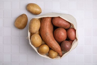 Photo of Different types of fresh potatoes in bag on white table, top view