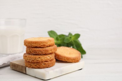 Photo of Tasty sweet sugar cookies and mint on white wooden table, closeup. Space for text