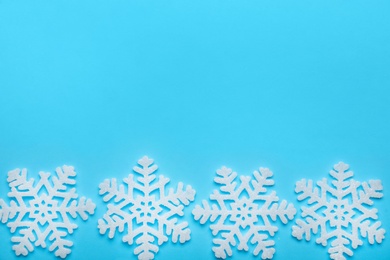 Beautiful decorative snowflakes on light blue background, flat lay. Space for text