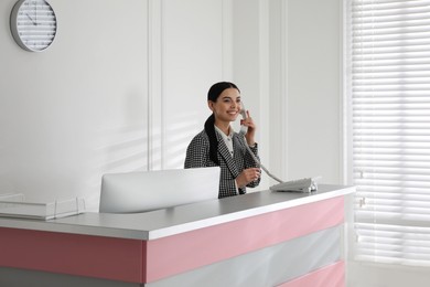 Photo of Receptionist talking on phone at countertop in office