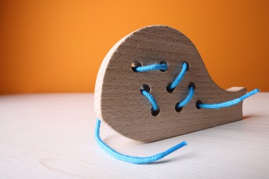 Photo of Wooden lacing toy on light table, closeup and space for text. Motor skills development