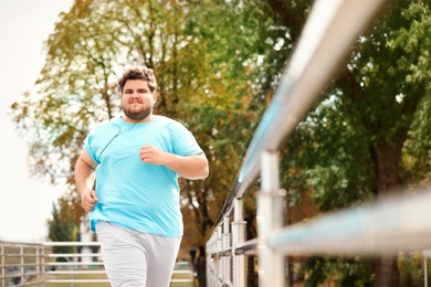 Photo of Young overweight man running outdoors. Fitness lifestyle