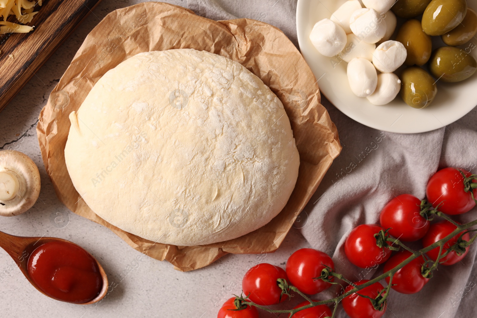 Photo of Pizza dough and products on gray textured table, flat lay