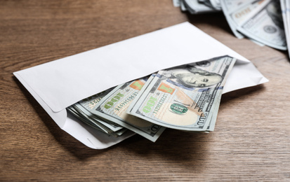 Envelope with dollar bills on wooden table. Bribe concept