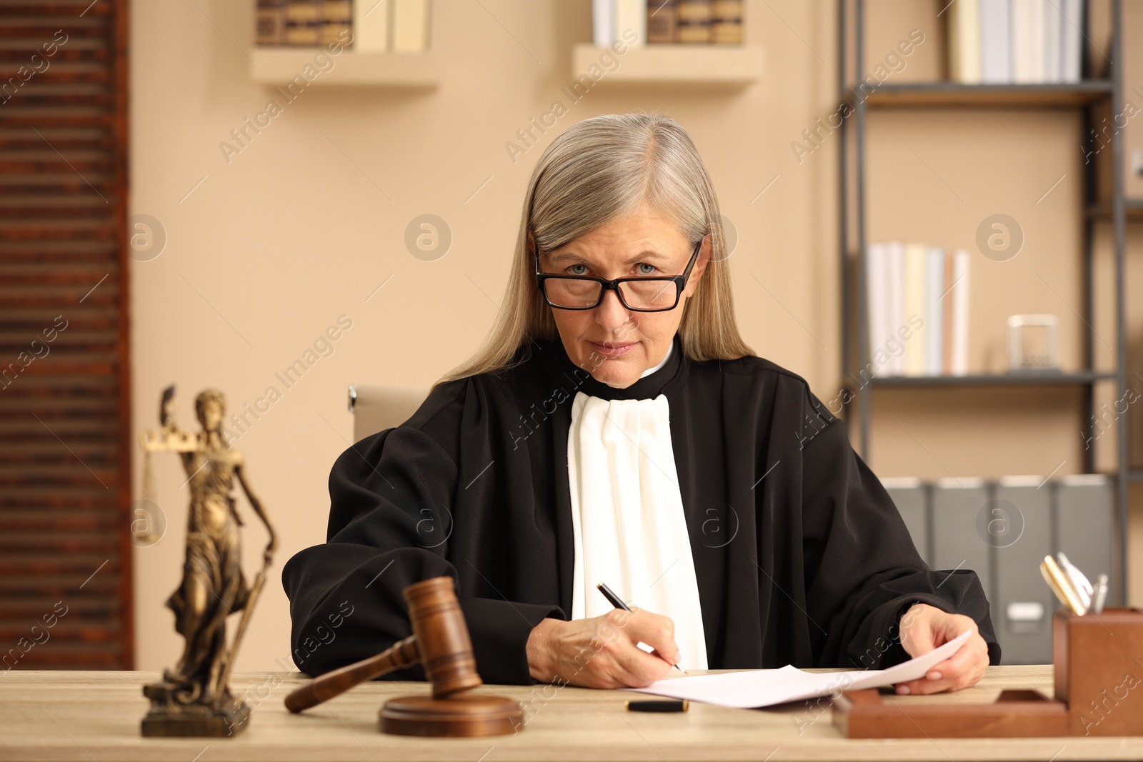 Photo of Judge in court dress working at table indoors