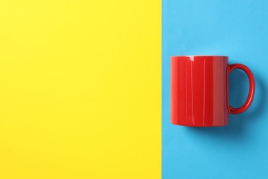 Photo of One red ceramic mug on color background, top view. Space for text