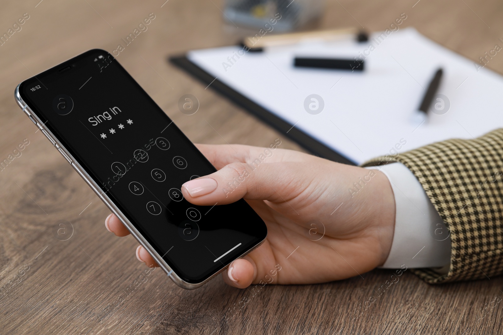 Photo of Woman unlocking smartphone with blocked screen at wooden table, closeup