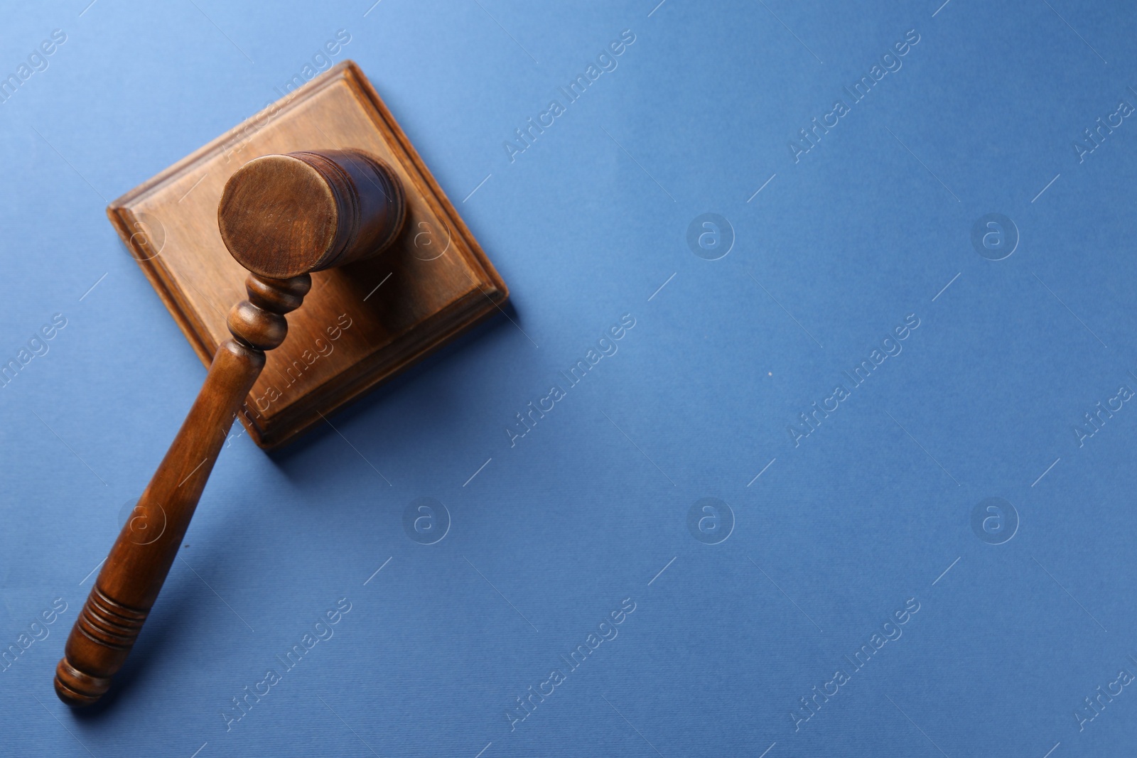 Photo of Wooden gavel and sound block on blue table, top view. Space for text