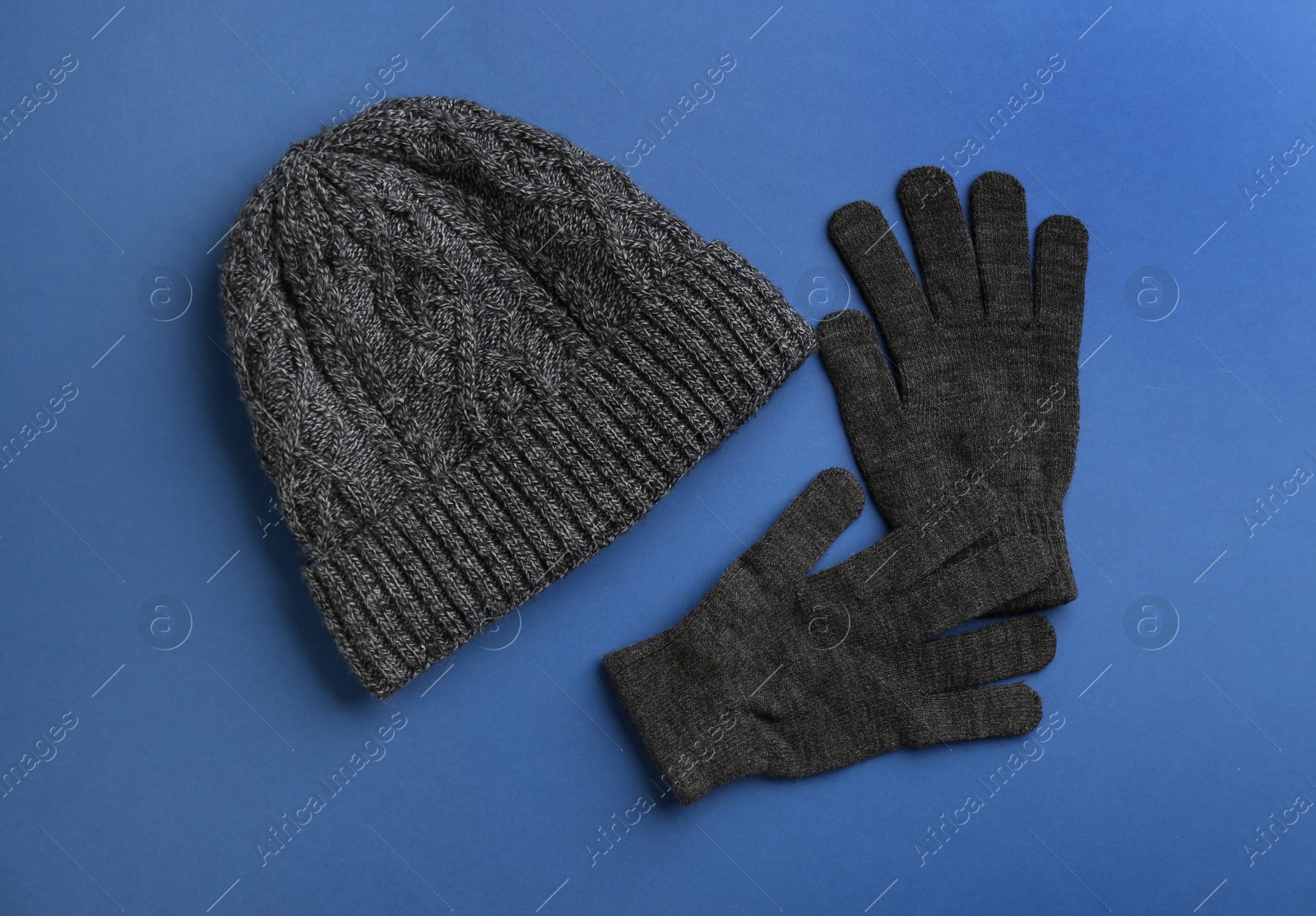 Photo of Woolen gloves and hat on blue background, flat lay