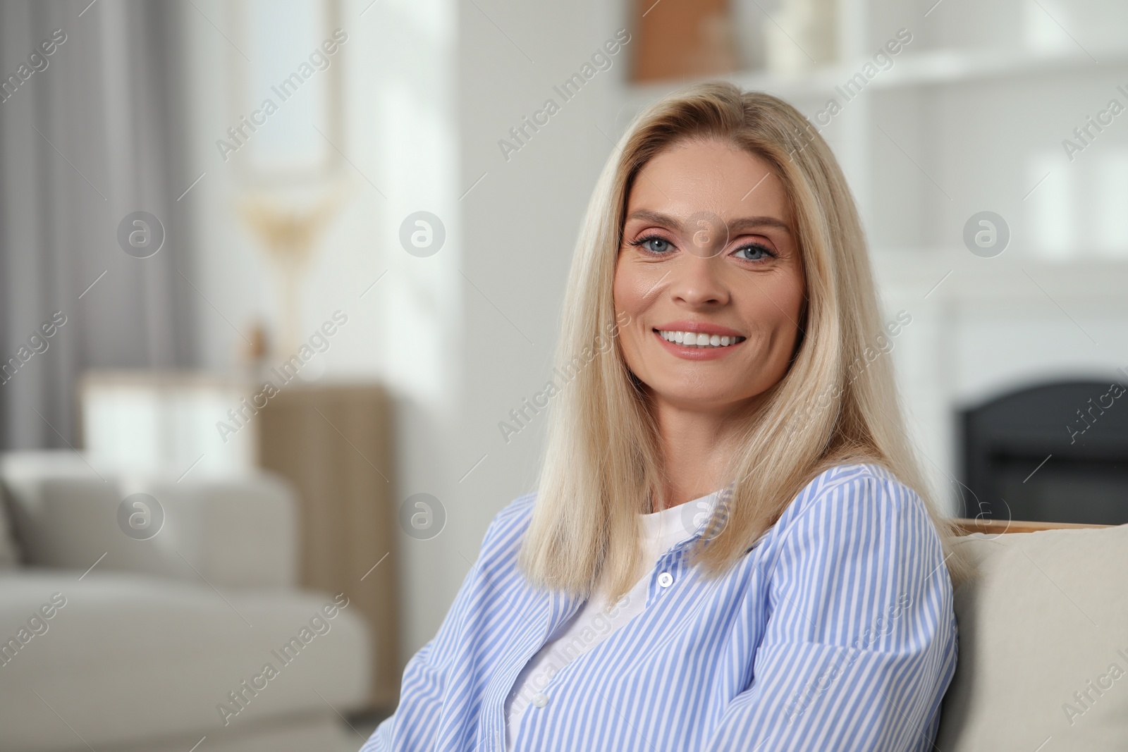 Photo of Portrait of smiling middle aged woman with blonde hair at home. Space for text