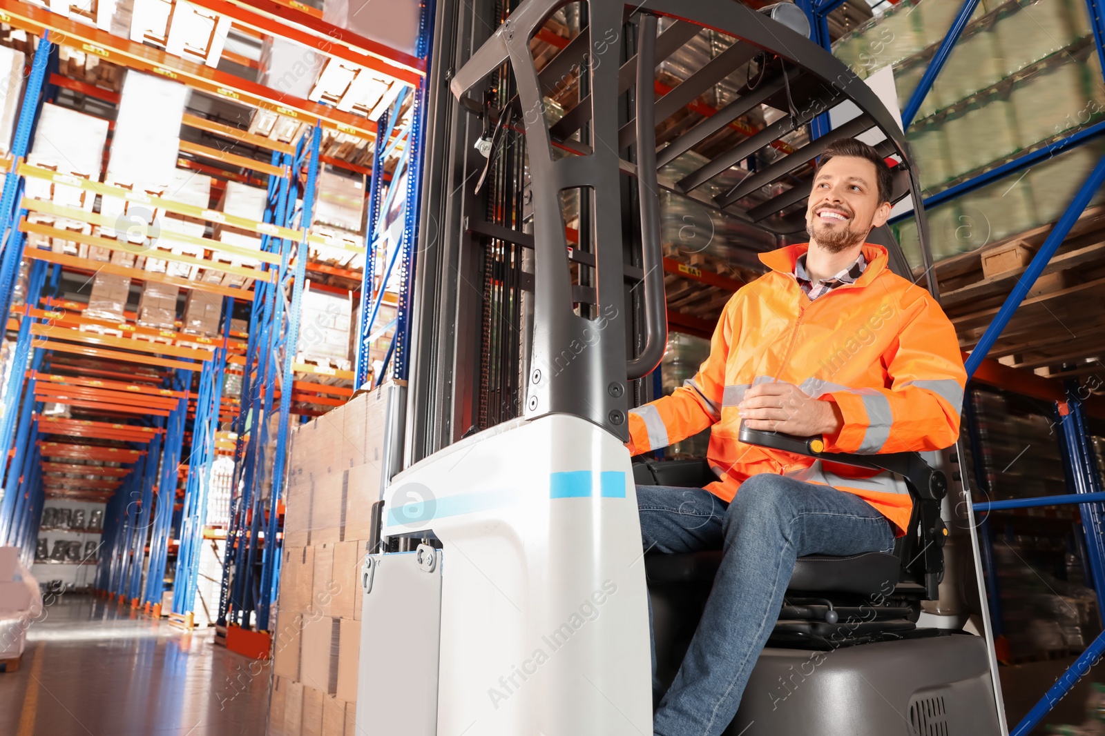 Photo of Happy worker sitting in forklift truck at warehouse