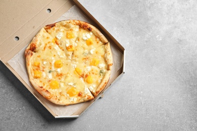 Cheese pizza in carton box on grey background, top view with space for text. Food delivery service