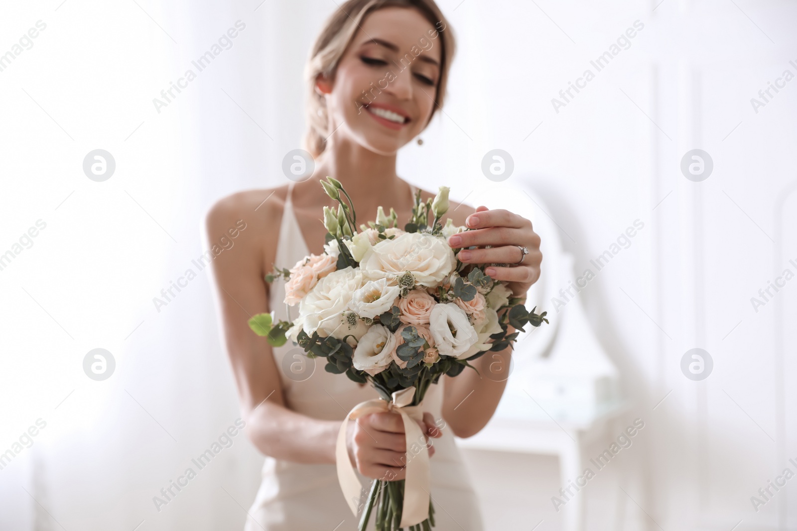 Photo of Young bride with beautiful wedding bouquet in room focus on flowers