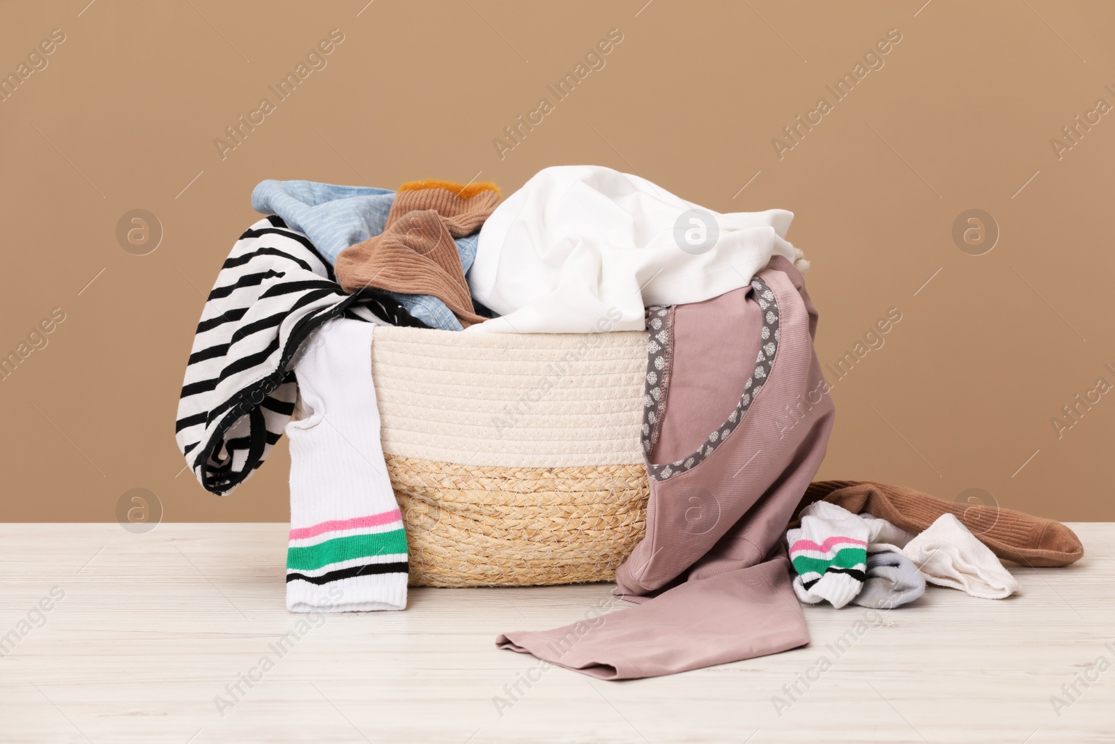 Photo of Wicker laundry basket with clothes near beige wall