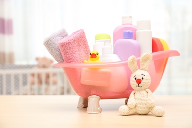 Photo of Baby cosmetic products, toys and towels on table indoors