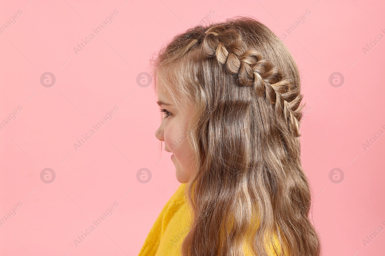 Photo of Cute little girl with braided hair on pink background