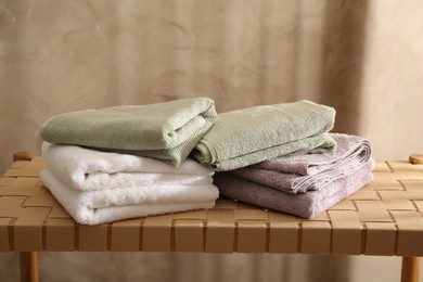 Photo of Stacks of soft towels on wicker bench indoors