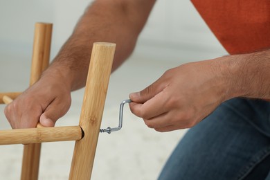 Photo of Man with hex key assembling furniture on blurred background, closeup