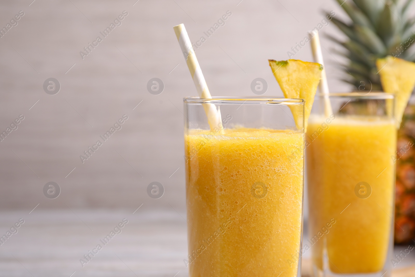 Photo of Tasty pineapple smoothie on table, closeup. Space for text
