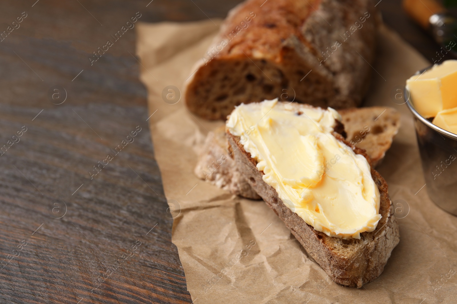 Photo of Tasty bread with butter on wooden table, closeup. Space for text