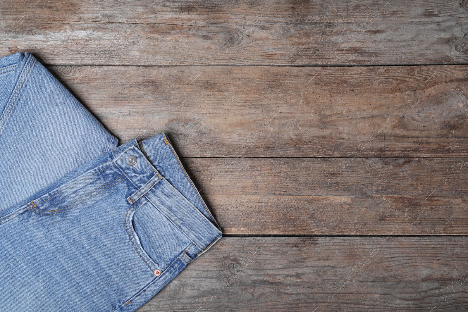 Photo of Stylish jeans on wooden background, top view. Space for text