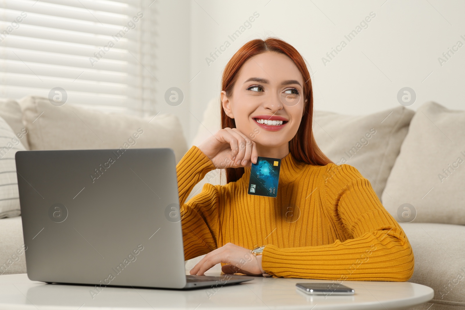 Photo of Happy woman with credit card near laptop at home. Online shopping