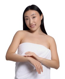 Beautiful young Asian woman applying body cream onto arm on white background