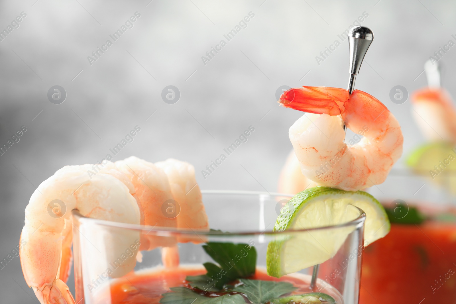 Photo of Tasty shrimp cocktail with sauce in glass on blurred background, closeup