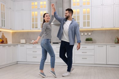 Photo of Happy lovely couple dancing together in kitchen