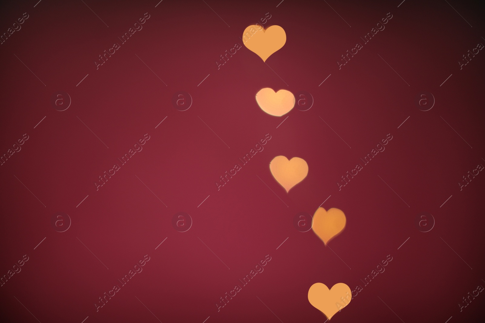 Photo of Blurred view of beautiful lights on burgundy background, space for text. Bokeh effect