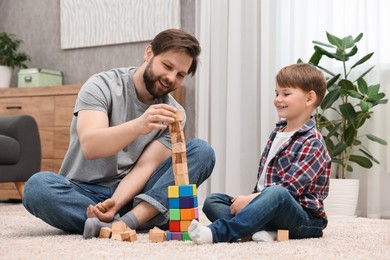 Photo of Happy dad and son building tower with cubes at home