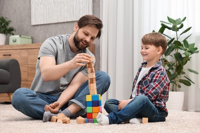 Happy dad and son building tower with cubes at home