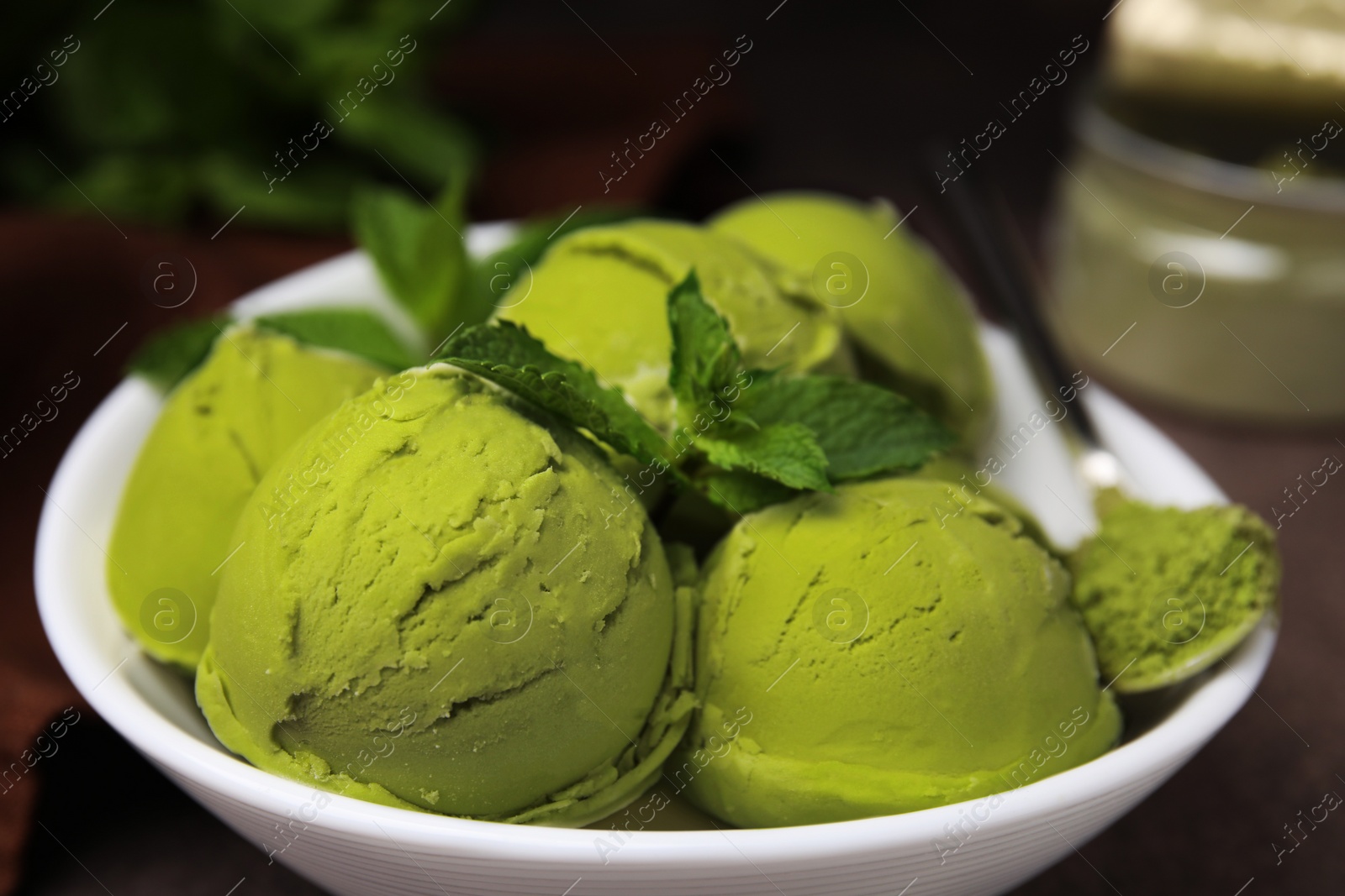 Photo of Tasty matcha ice cream and spoon with powder in bowl on table, closeup