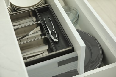 Open drawers of kitchen cabinet with different dishware and utensils, closeup