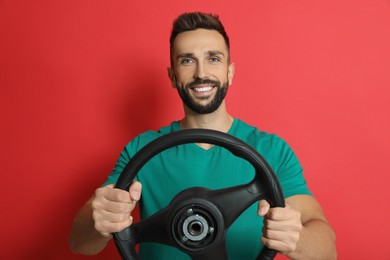 Photo of Happy man with steering wheel on red background