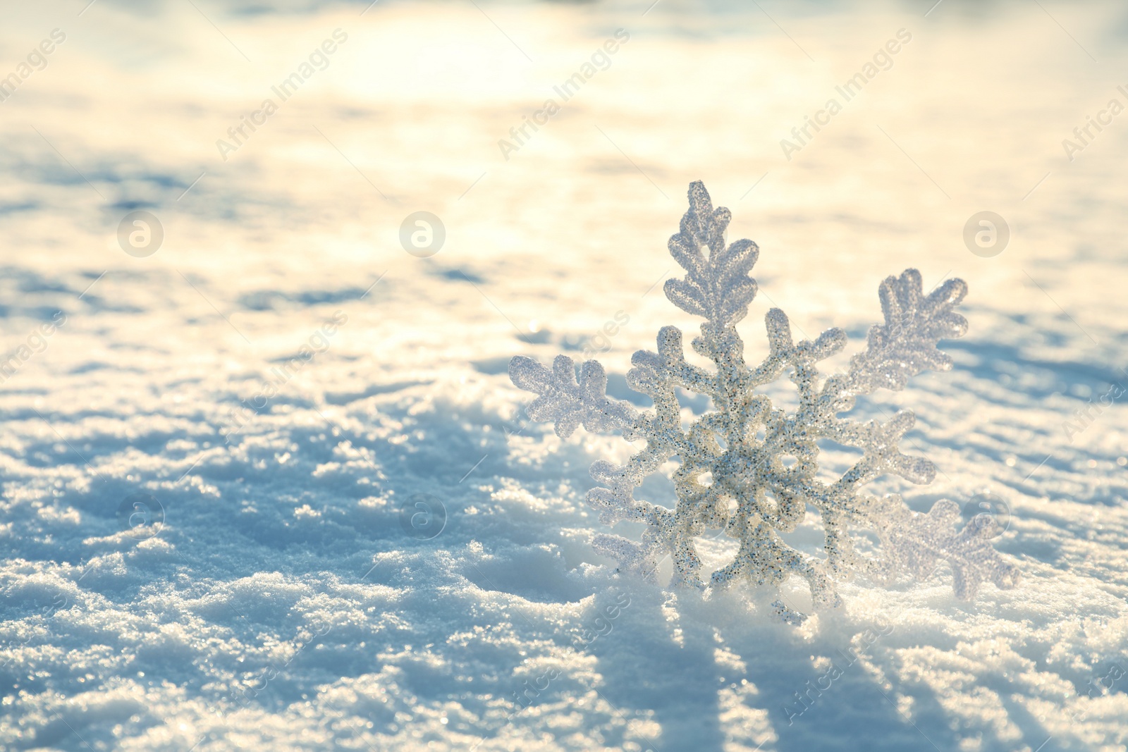 Photo of Beautiful decorative snowflake in white snow, outdoors. Space for text