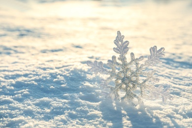 Beautiful decorative snowflake in white snow, outdoors. Space for text